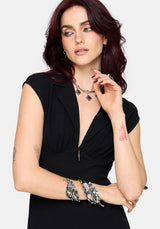 Woman wearing a black dress with with silver jewellery on a white background