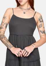 Woman wearing a grey midi dress with tattoos on arms and neck against a white background
