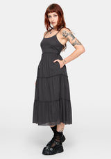 Woman wearing a grey midi dress with tattoos on arms and neck against a white background