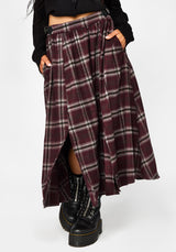 A person wearing a long plaid skirt in burgundy, black, and white, paired with black lace-up boots, shown from the waist down against a light gray studio background.