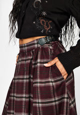 Close-up of a person wearing a dark burgundy plaid pleated skirt with a black belt and a black cropped cardigan with embroidered details.