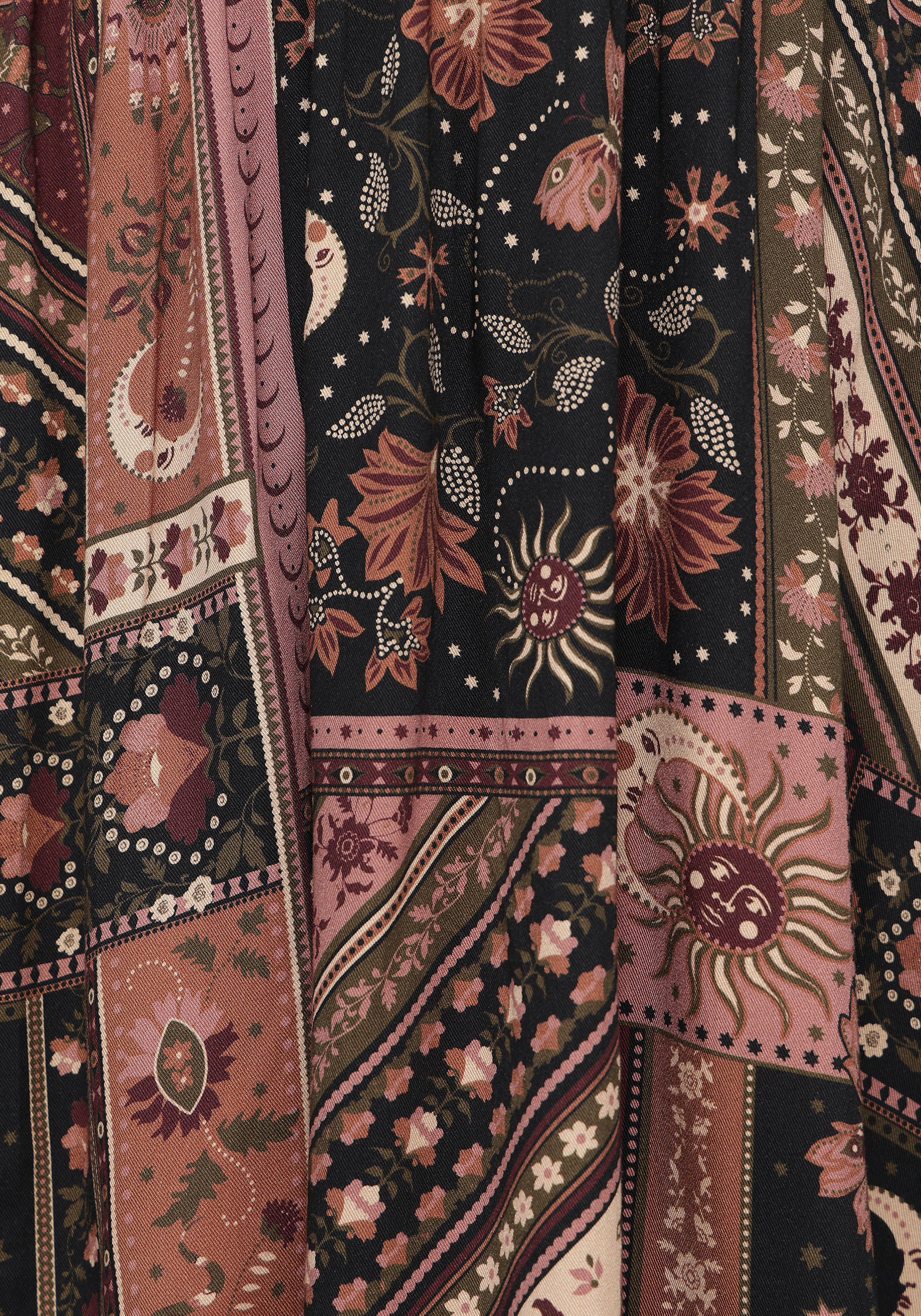 A close-up of a patchwork print mini dresses with mixed panels in dusty pink, rust red, black, and beige, featuring floral, sunburst, and geometric motifs.