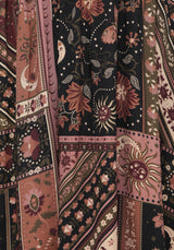 A close-up of a patchwork print mini dresses with mixed panels in dusty pink, rust red, black, and beige, featuring floral, sunburst, and geometric motifs.