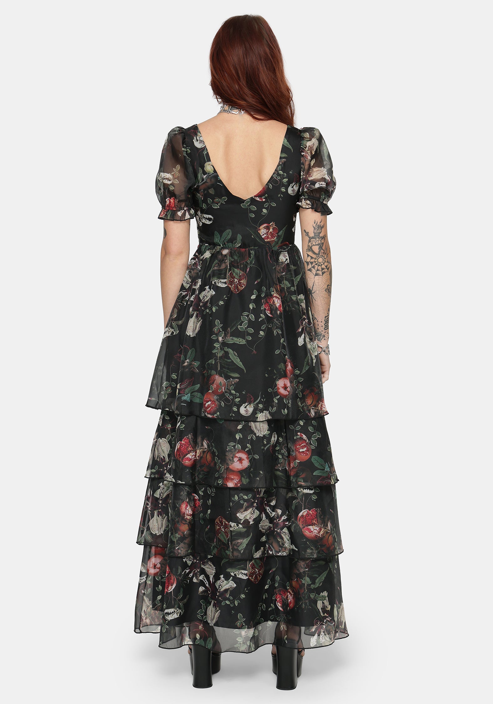 Woman wearing a fruit printed ruffle maxi dress with a white background