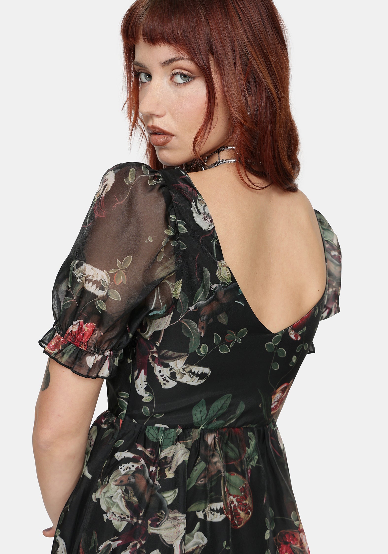 Woman wearing a fruit printed maxi dress with sheer black sleeves on a white background