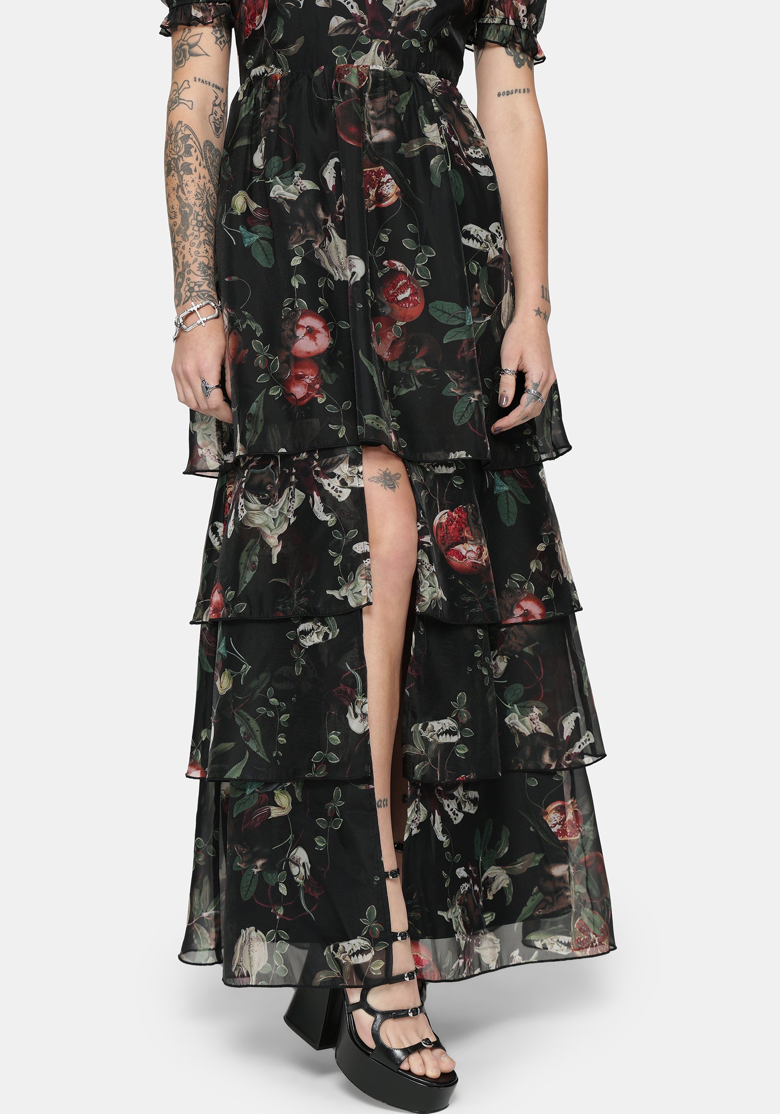 Woman wearing a black fruit printed maxi dress with tiered layers on a white background