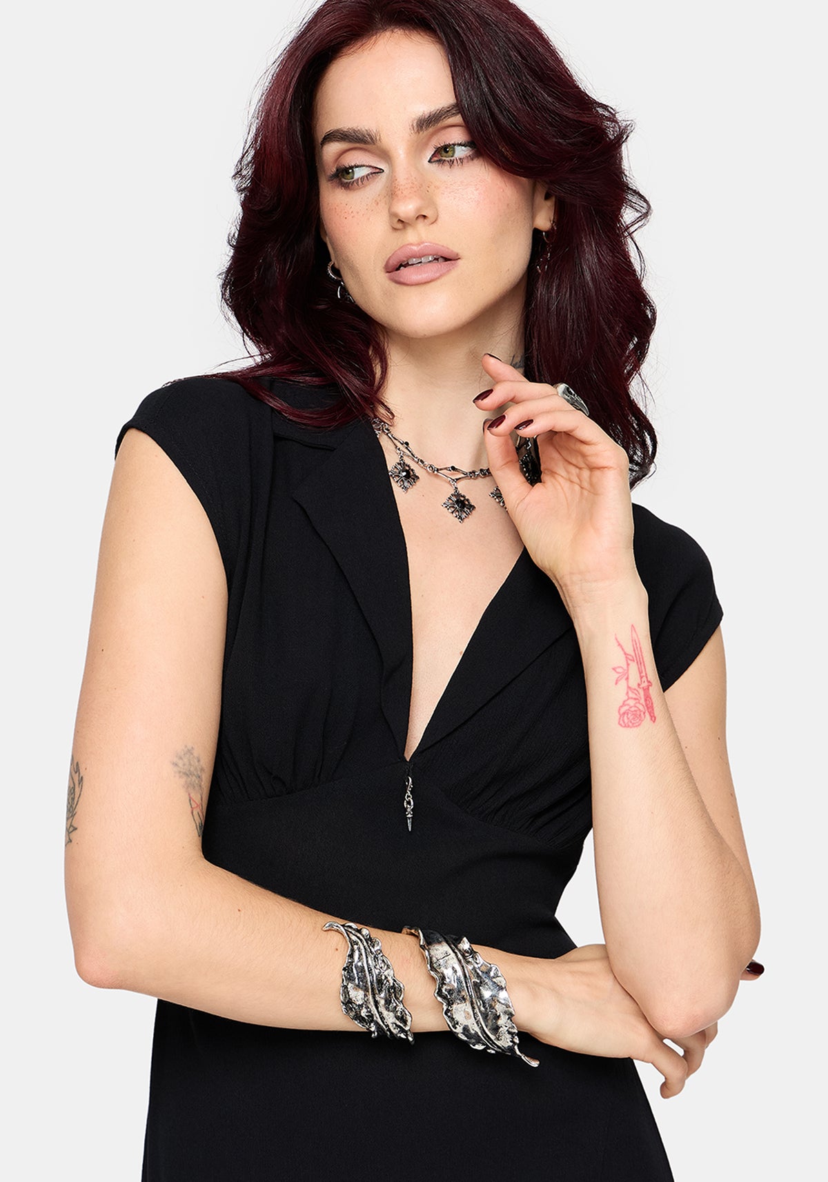 Woman wearing a black dress with with silver jewellery on a white background