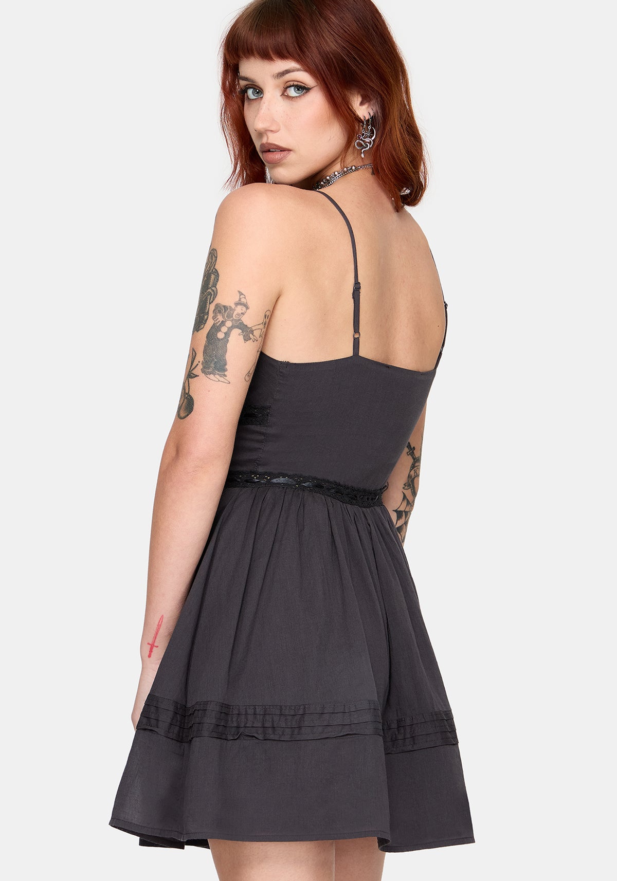 Woman wearing a grey dress with thin straps on a white background