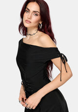 A woman modeling a black off-the-shoulder dress with side lace-up details, photographed against a light gray studio background.