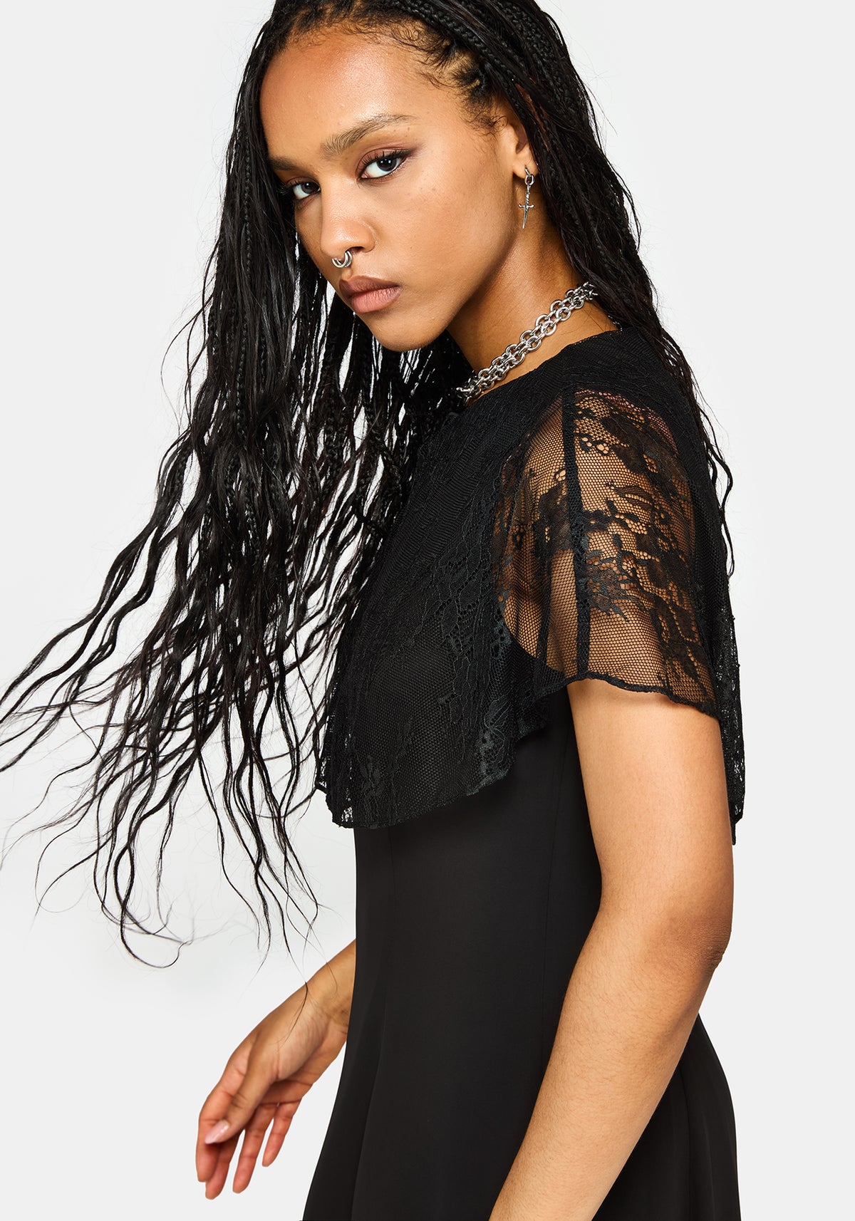 A woman modeling a black dress with sheer lace flutter sleeves, photographed against a light gray studio background.