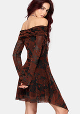 A woman modeling an off-the-shoulder long-sleeve mini dress with a burnt orange and black floral lace flocked pattern, against a light gray studio background.