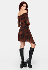 A woman modeling an off-the-shoulder mini dress with a burnt orange and black floral pattern, paired with black knee-high platform boots, against a light gray studio background.