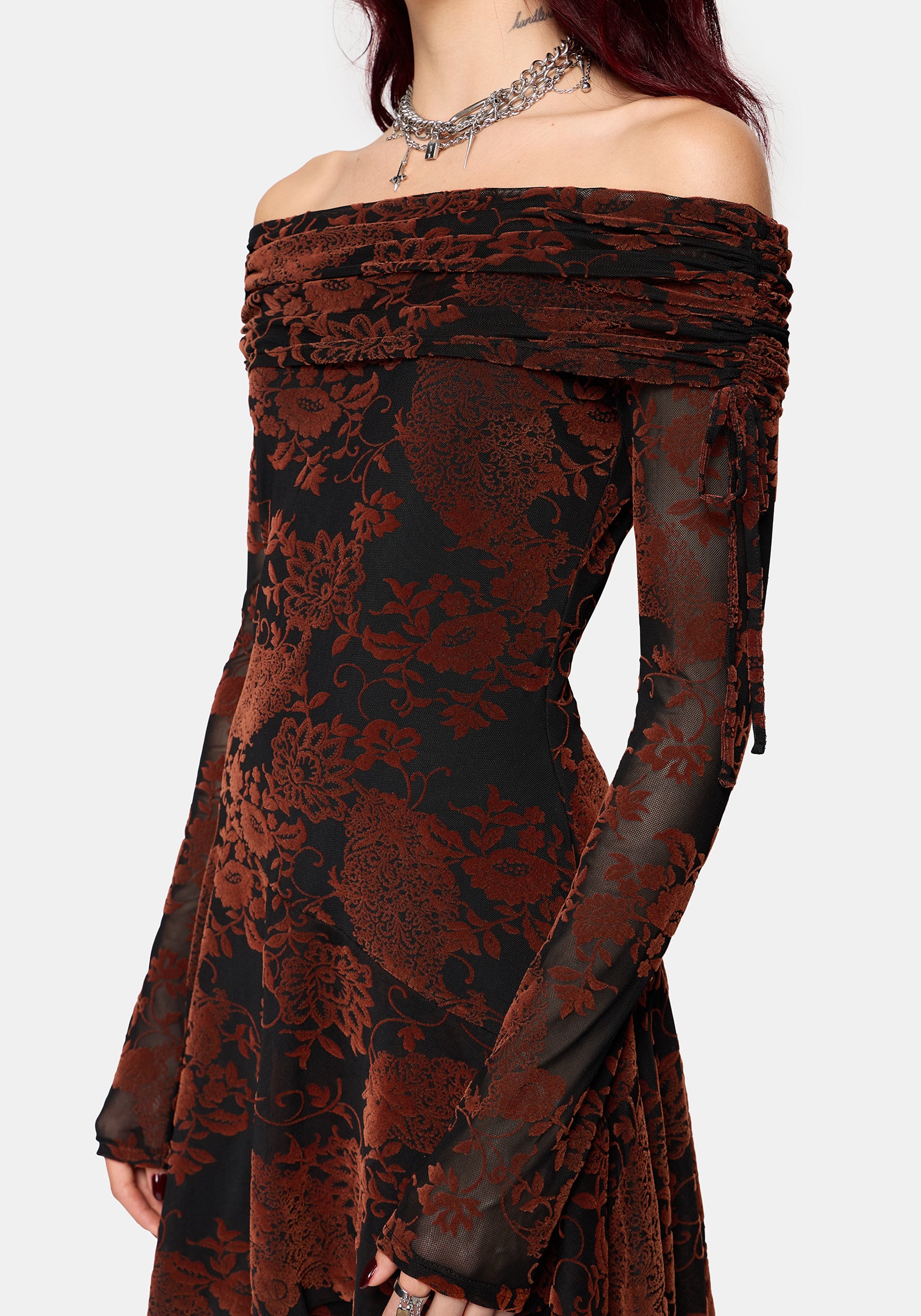 An off-the-shoulder long-sleeve mini dress featuring a burnt orange flocked pattern and black base, shown on a model against a light gray background.