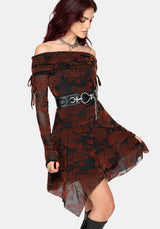A woman modeling an off-the-shoulder gothic-style dress with a black and burnt orange floral lace overlay and sheer dark red lining, accessorized with a wide black waist belt featuring silver charms.