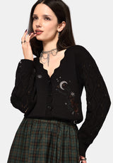 Woman wearing a black cardigan with celestial designs on a white background