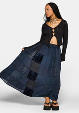Woman wearing a black top and long navy plaid skirt on a white background