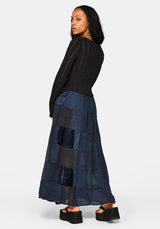 Woman wearing a black top and blue patchwork skirt on a white background