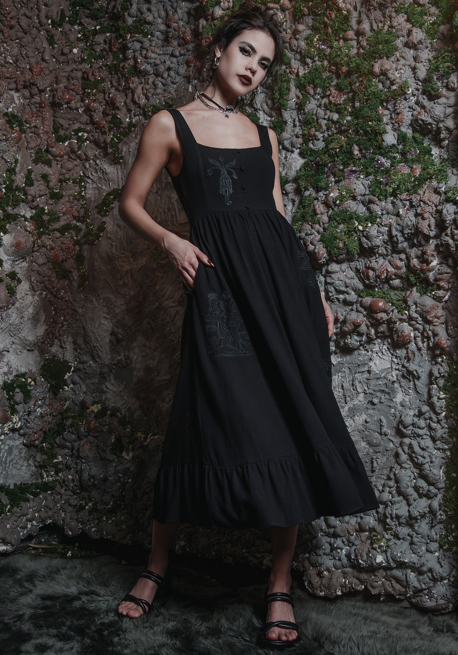 Black embroidered midi dress beside an old wall
