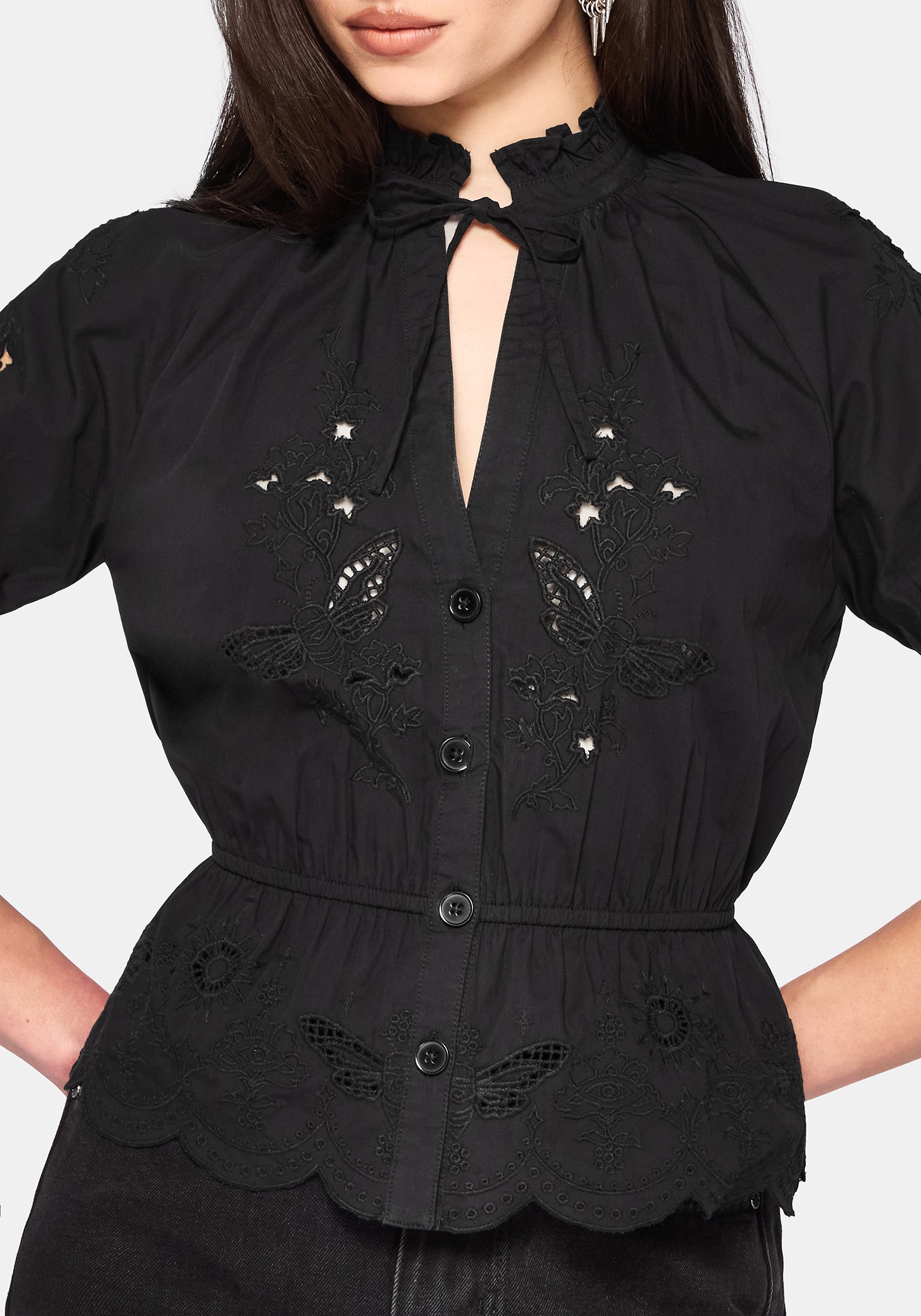 Woman wearing a black blouse with floral cut out details on a white background
