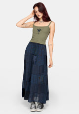 Woman wearing a khaki sleeveless vest with thin straps, cropped length and blue butterfly embroidery in center against a white studio background