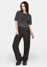 A model wearing a washed charcoal cropped t-shirt with a skull graphic and black wide-leg pants, standing against a light gray studio background.