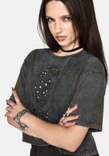 A woman wearing a dark gray washed short-sleeve crop top with cutout details on the front, styled with a black choker and silver bracelets against a light gray background.